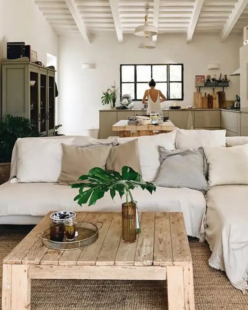 Open living room with a white slipcovered sectional, beige pillows, a chunky reclaimed wood coffee table and a sisal rug