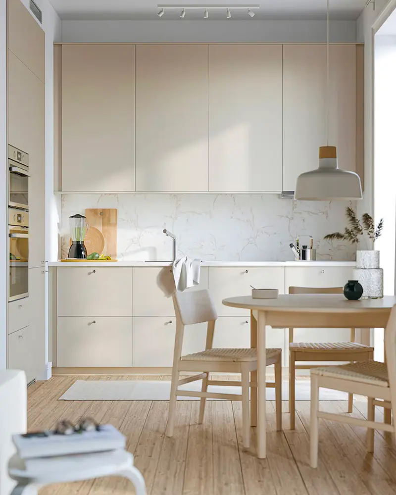 Beige handleless kitchen with white pendant, light wood dining table and chairs