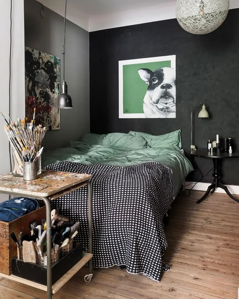 Dark bedroom with green bedding, bulldog print and metal cart