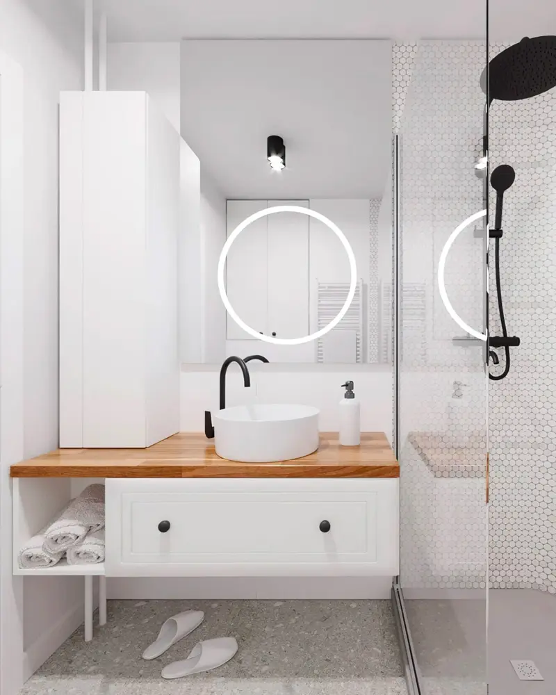 White bathroom with backlit round mirror, wood shelf vanity with white basin and black faucet