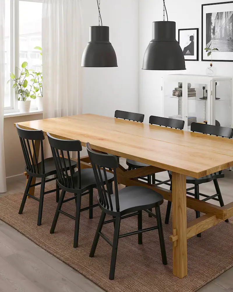 Long pine trestle table with black spindle chairs, two black pendants and jute rug