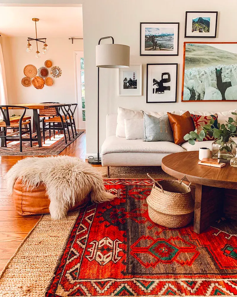 Red Oriental rug, sheepskin on a leather pouf, round wood coffee table and framed black and white prints