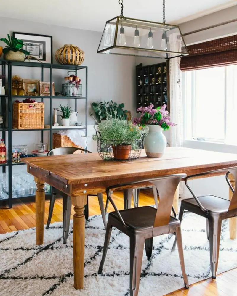 Turned-leg wood table with metal chairs, a glass lantern pendant and black metal shelves