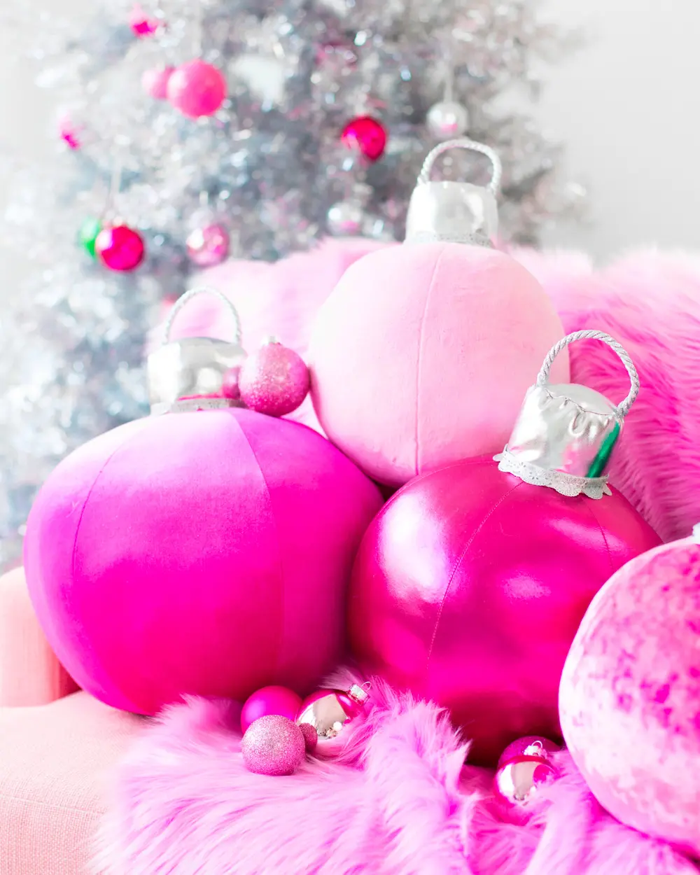 Plush pink velvet pillows shaped like round Christmas ornaments with silver caps