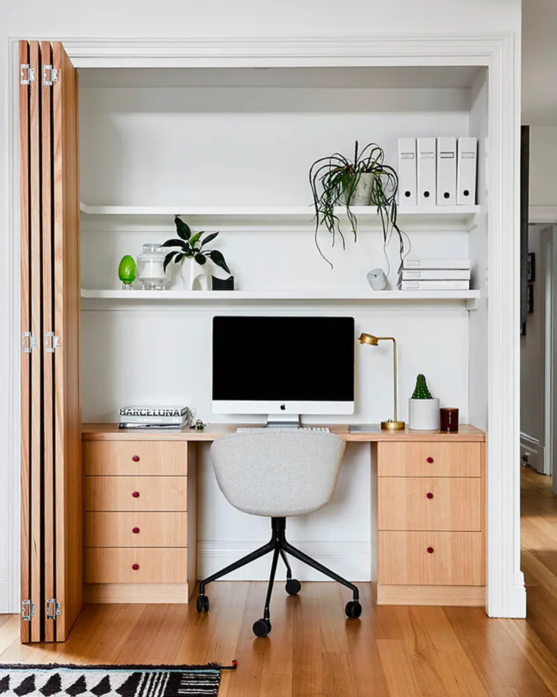 Closet office with bifold doors, white shelves, iMac and wood drawer units