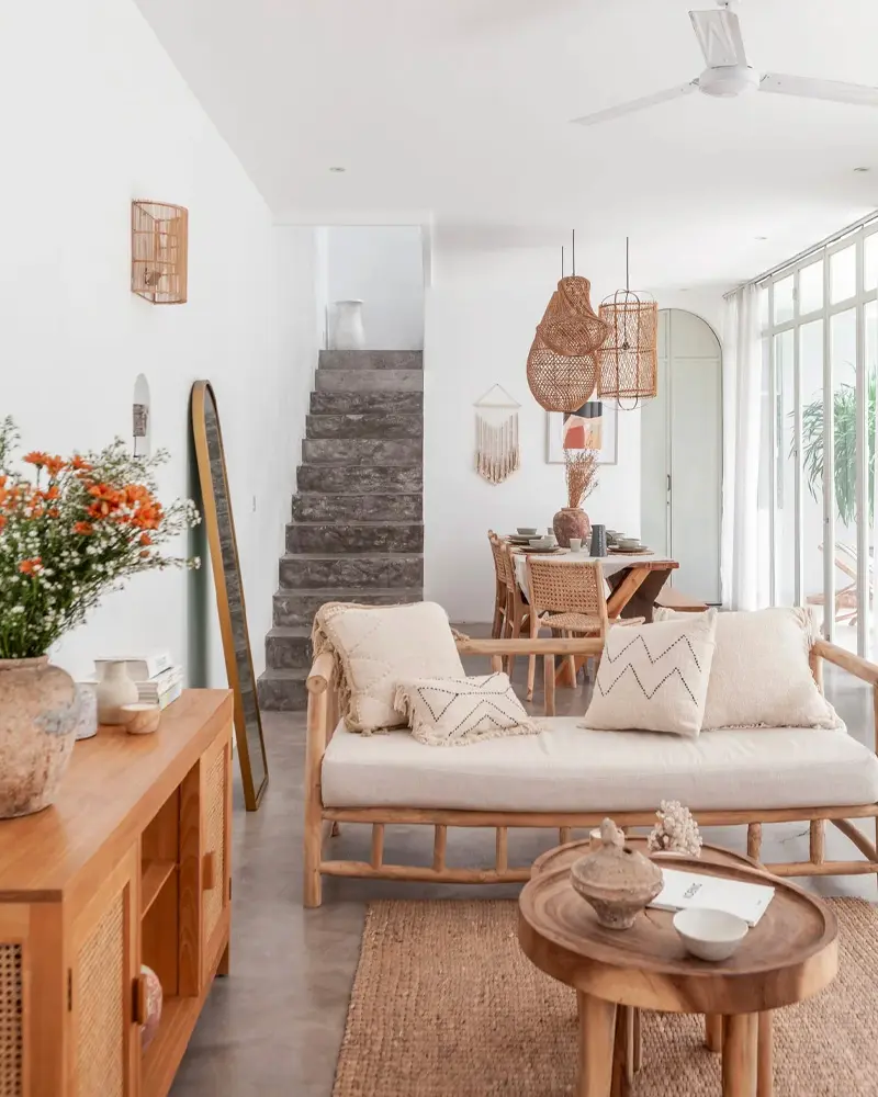 Bamboo daybed with white cushions, stair with rattan pendant, round wood side table and flowers