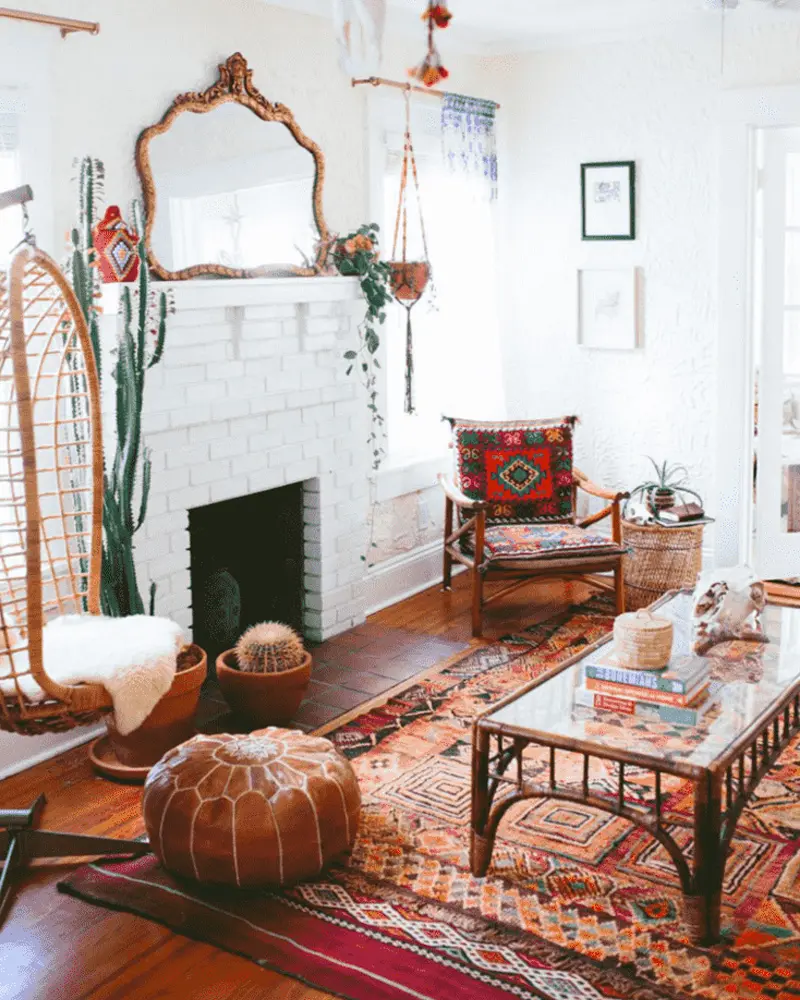 White brick fireplace, ornate mirror, leather pouf, kilim rugs and hanging rattan chair