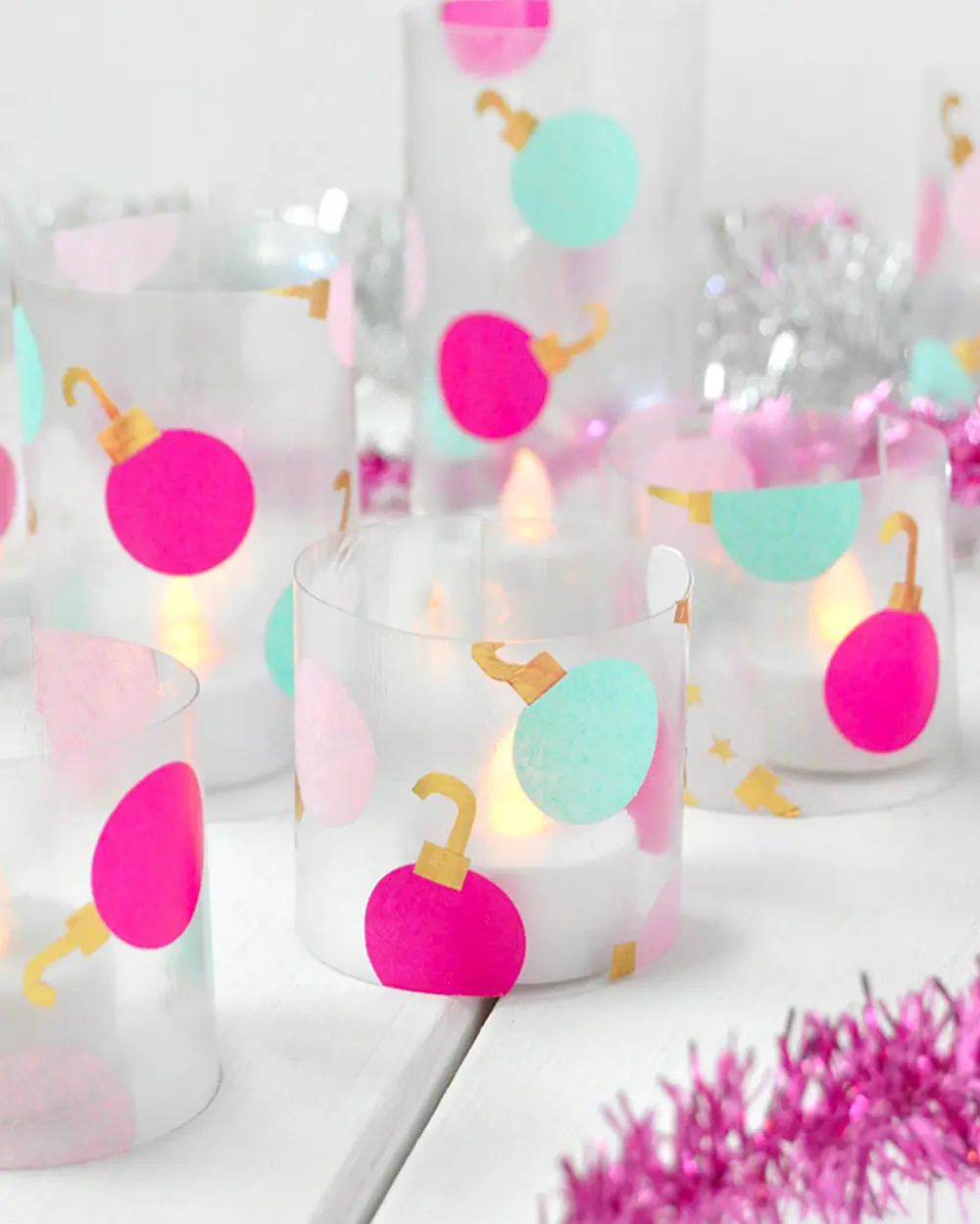 Vellum candle wraps decorated with bright pink and mint paper ornament shapes and LED tea lights