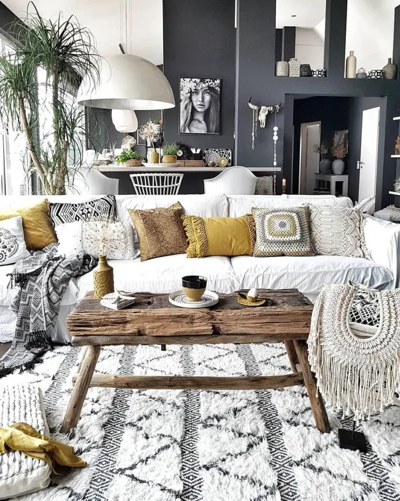 White sofa with mustard pillows, reclaimed wood coffee table, Berber rug and charcoal walls