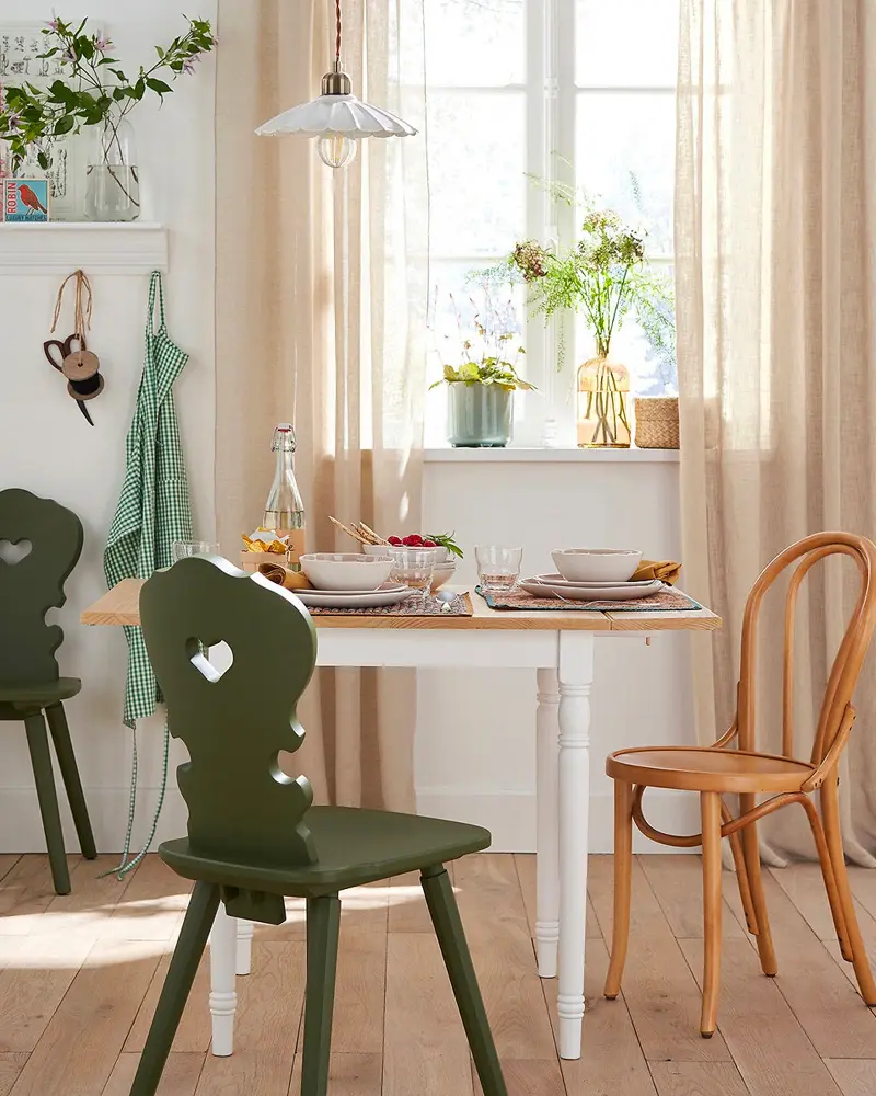 White table with green carved chair, bentwood chair, linen curtains and enamel pendant