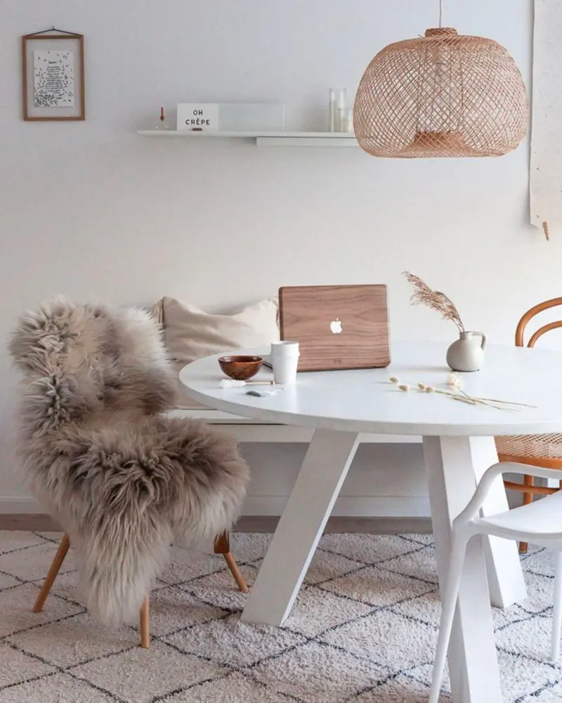 Round white table with sheepskin-covered chair, rattan pendant and Berber rug