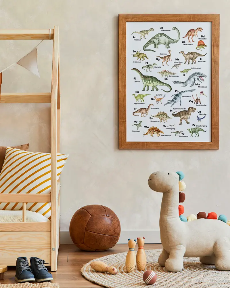 Dinosaur alphabet poster above a plush dinosaur, leather ball and wooden house bed
