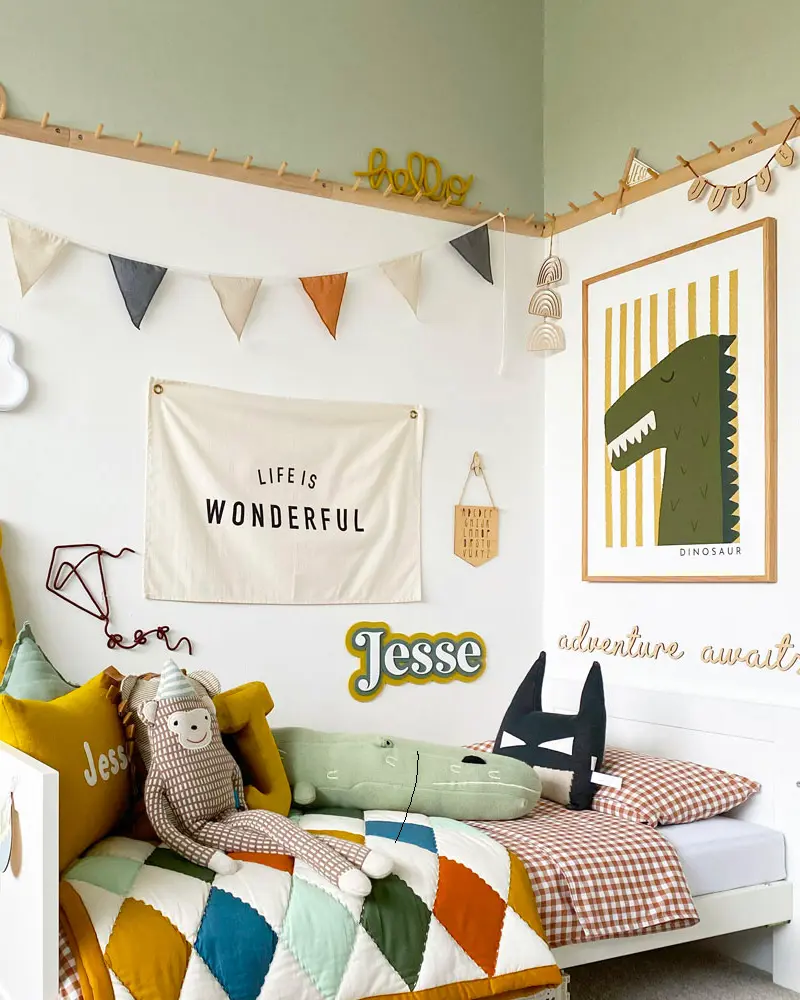 Kids bedroom with pennant bunting, dinosaur poster, mustard pillows and patchwork quilt