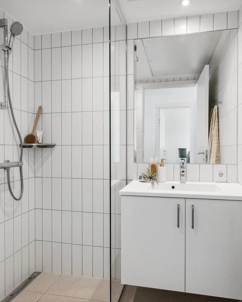 White bathroom with vertical stacked tiles, mirror and white vanity cabinet