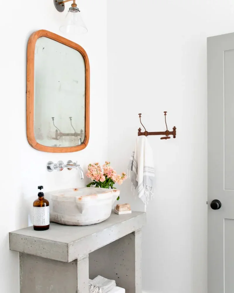 Concrete bathroom vanity with a stone vessel sink and wood-framed mirror