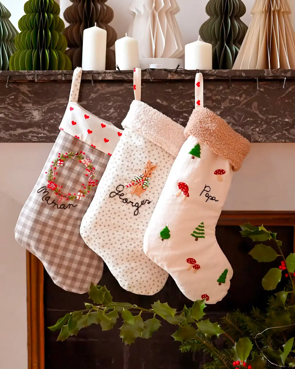 Three fabric stockings in gingham and printed cotton with embroidered names hanging from a mantel