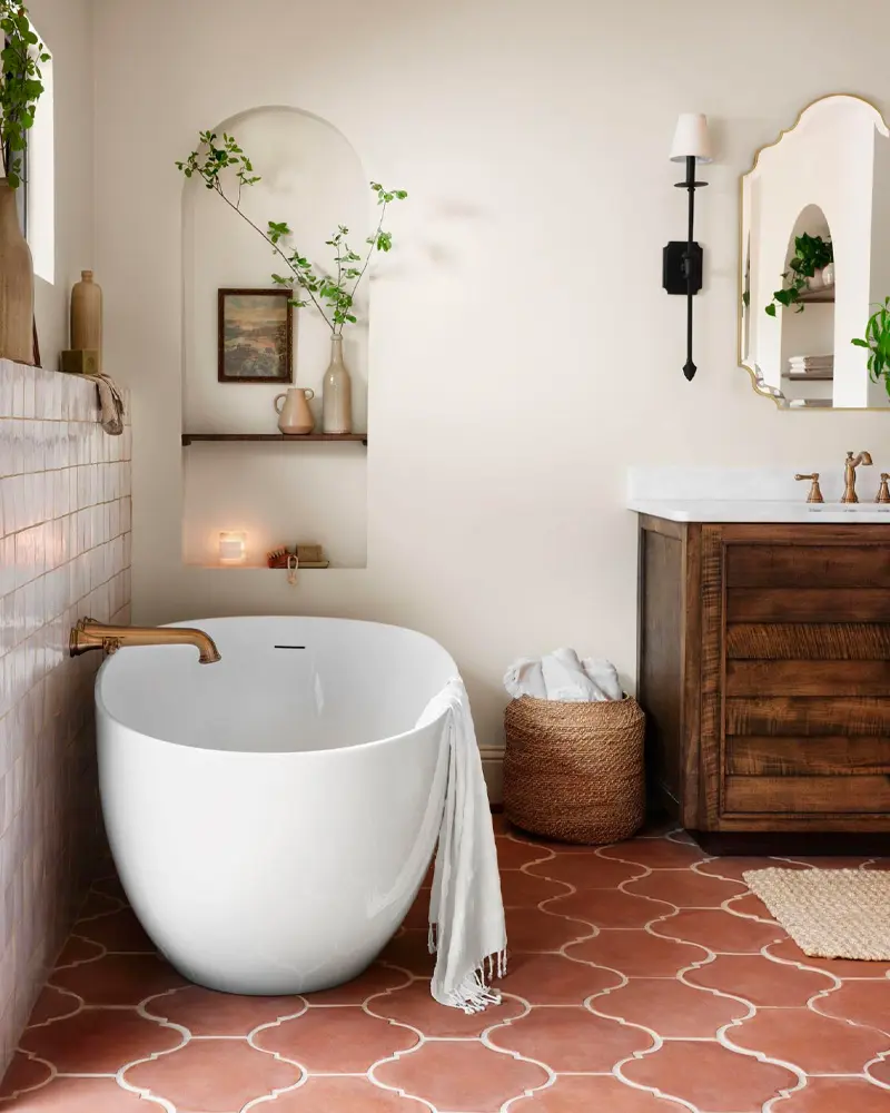 Bathroom with scalloped terracotta floor tiles, a white oval freestanding tub, a wood vanity and arched niches