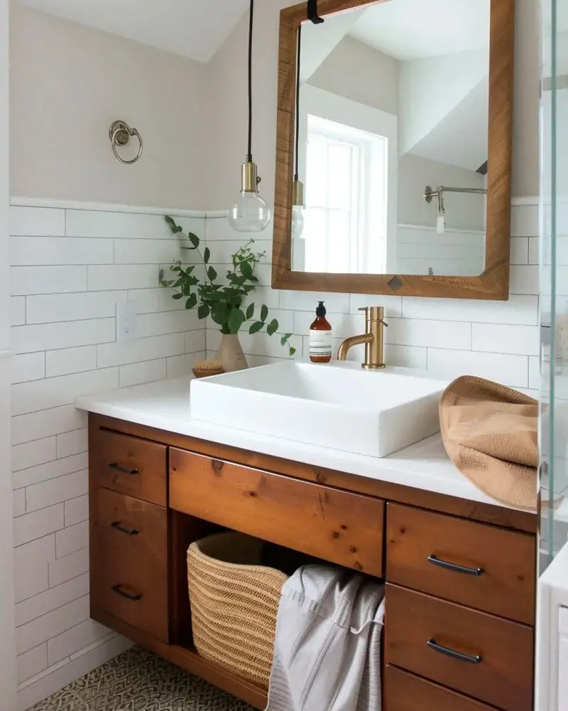 Warm wood vanity with drawers and an open shelf holding a basket, a white rectangular sink and a wood-framed mirror