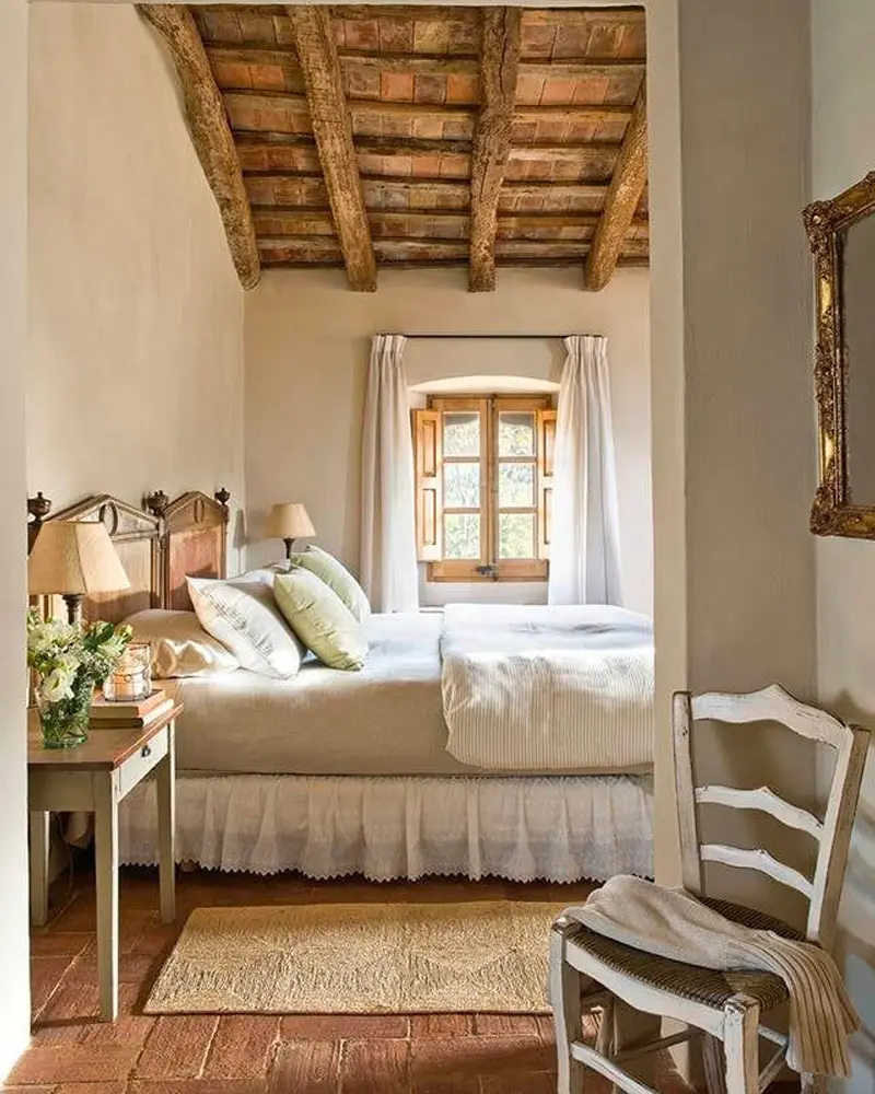 Brick and wood beamed ceiling, an old wooden window, a white bed and a rush-seat chair