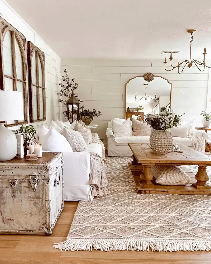 White sofas, a vintage trunk, a brass chandelier and arched window frames on shiplap