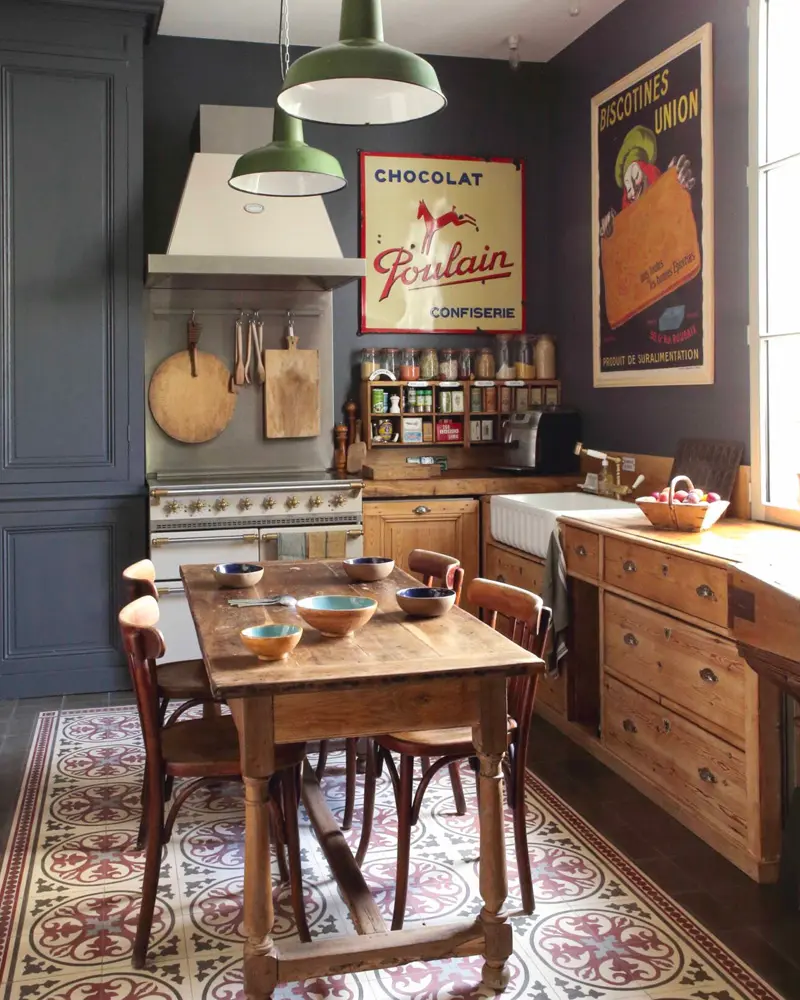 Navy walls with vintage food posters, a wooden farm table and a patterned tile floor