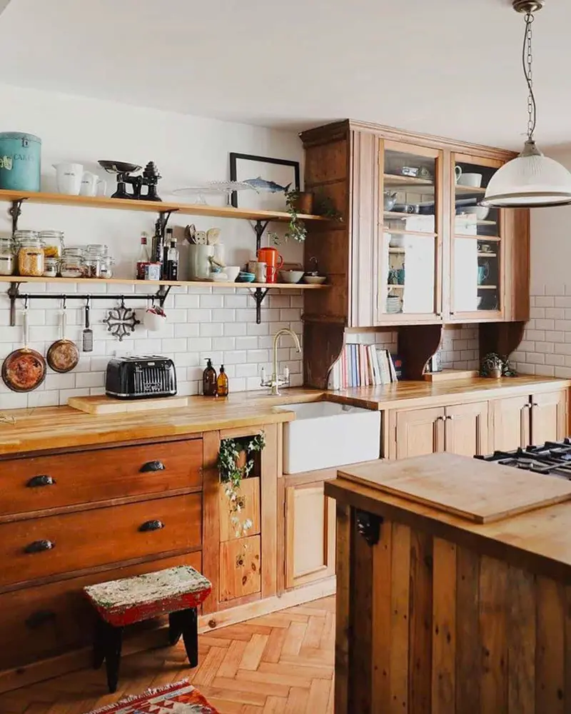 Vintage wood cabinets, open shelves with copper pans and a pendant light in a cozy kitchen