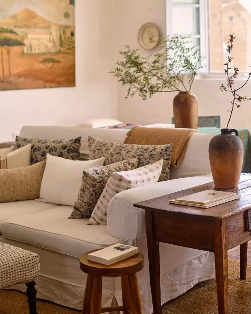 Cream sofa with block-print pillows, a dark wood console and a clay vase of branches