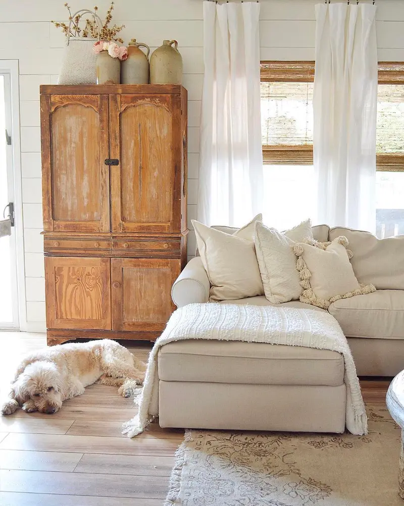 Antique pine armoire next to a white slipcovered sectional with a dog sleeping on the floor