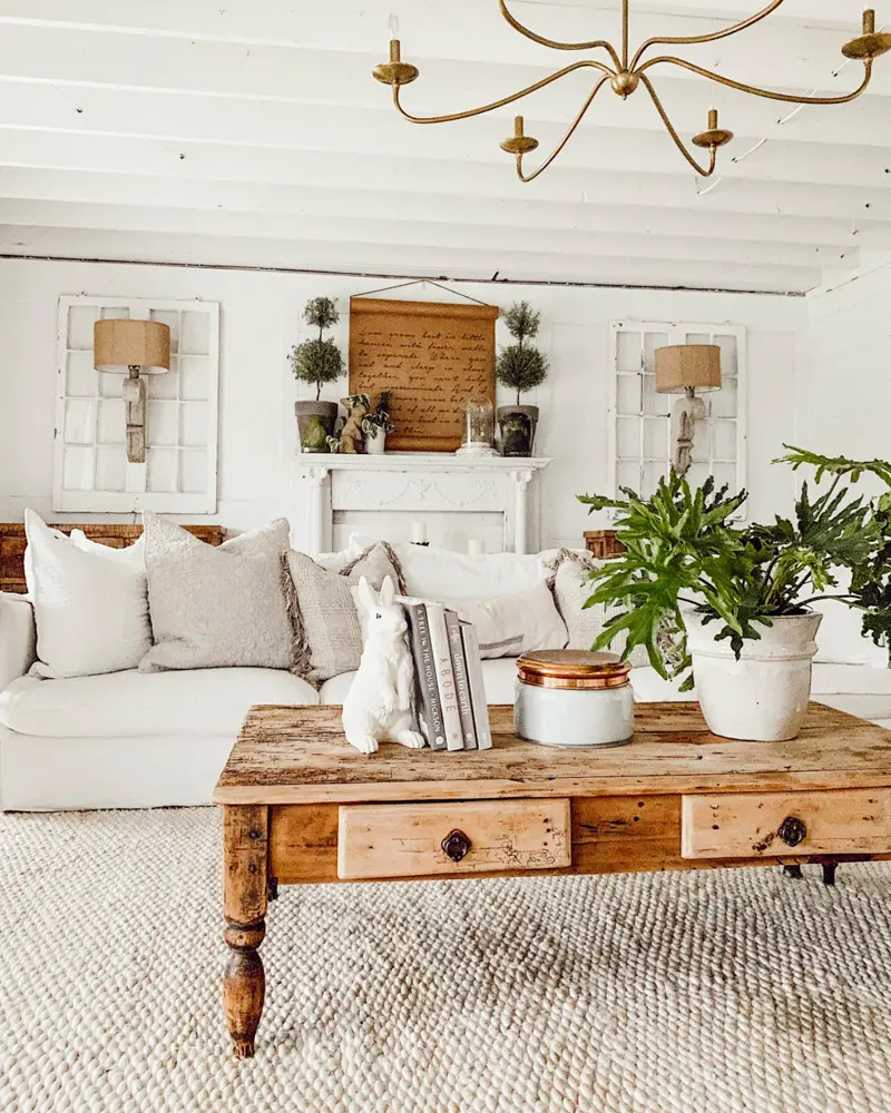 White sofa with a turned-leg pine coffee table, a brass chandelier and a potted fern