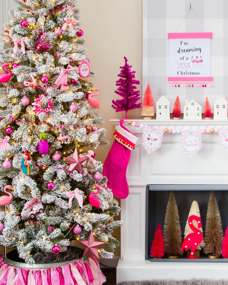 Flocked tree with fuchsia ornaments next to a white mantel with a hot pink stocking and a pink Christmas sign