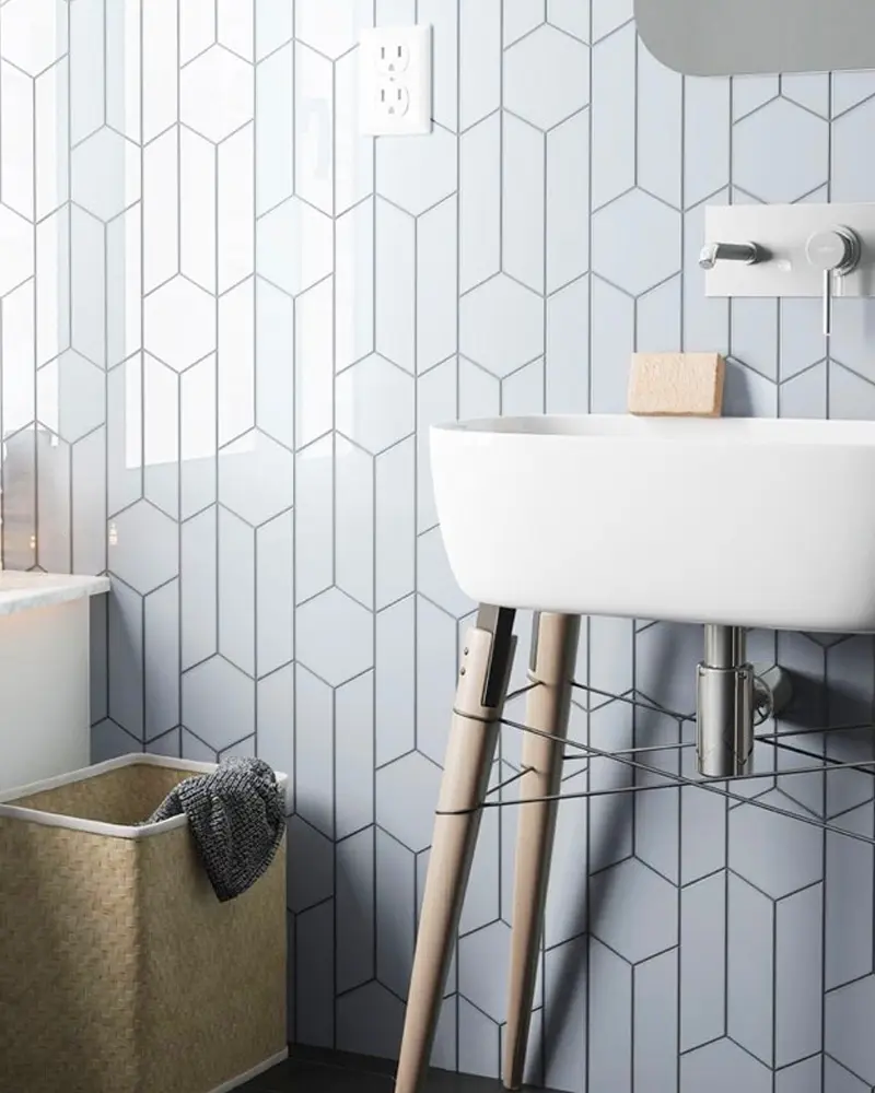 White chevron wall tiles with a wall-hung sink on wood legs and a woven laundry basket