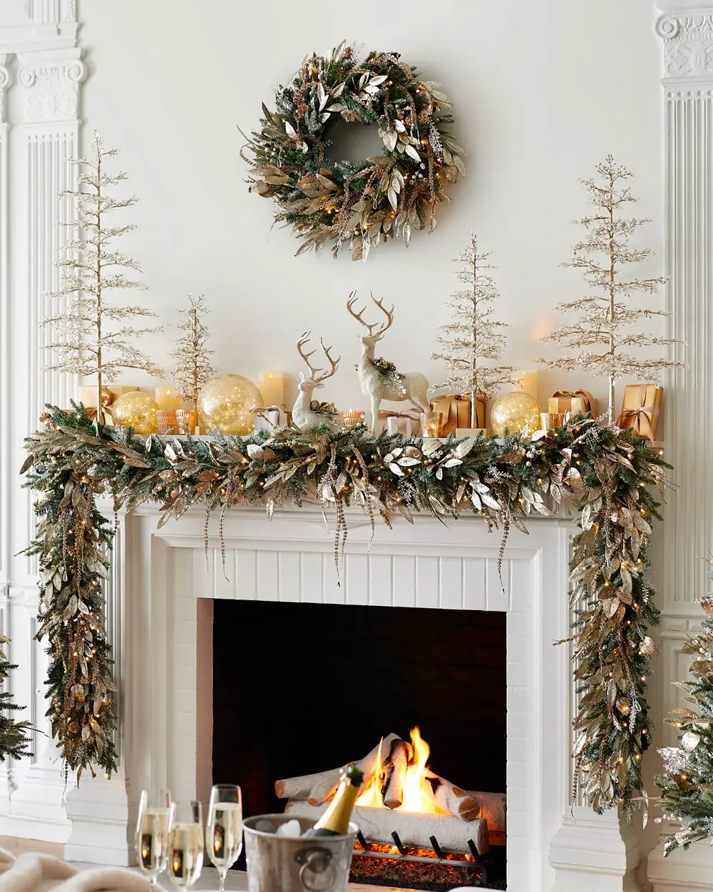 White fireplace with a gold-leaf garland, gold wreath, glitter trees and gold ornaments