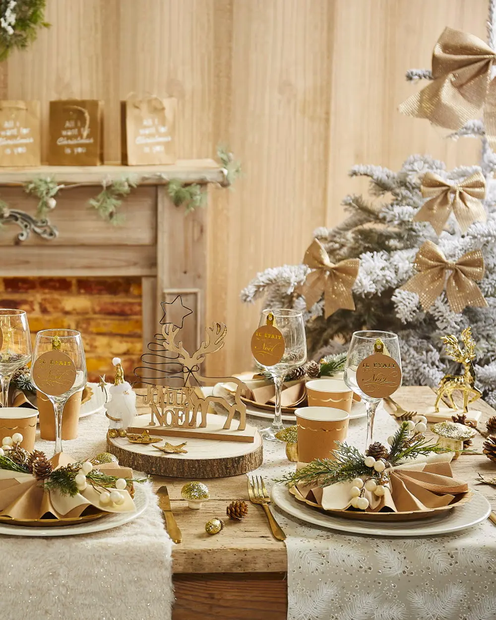 Christmas table with kraft-paper bows, gold place cards, wood slices and a flocked tree
