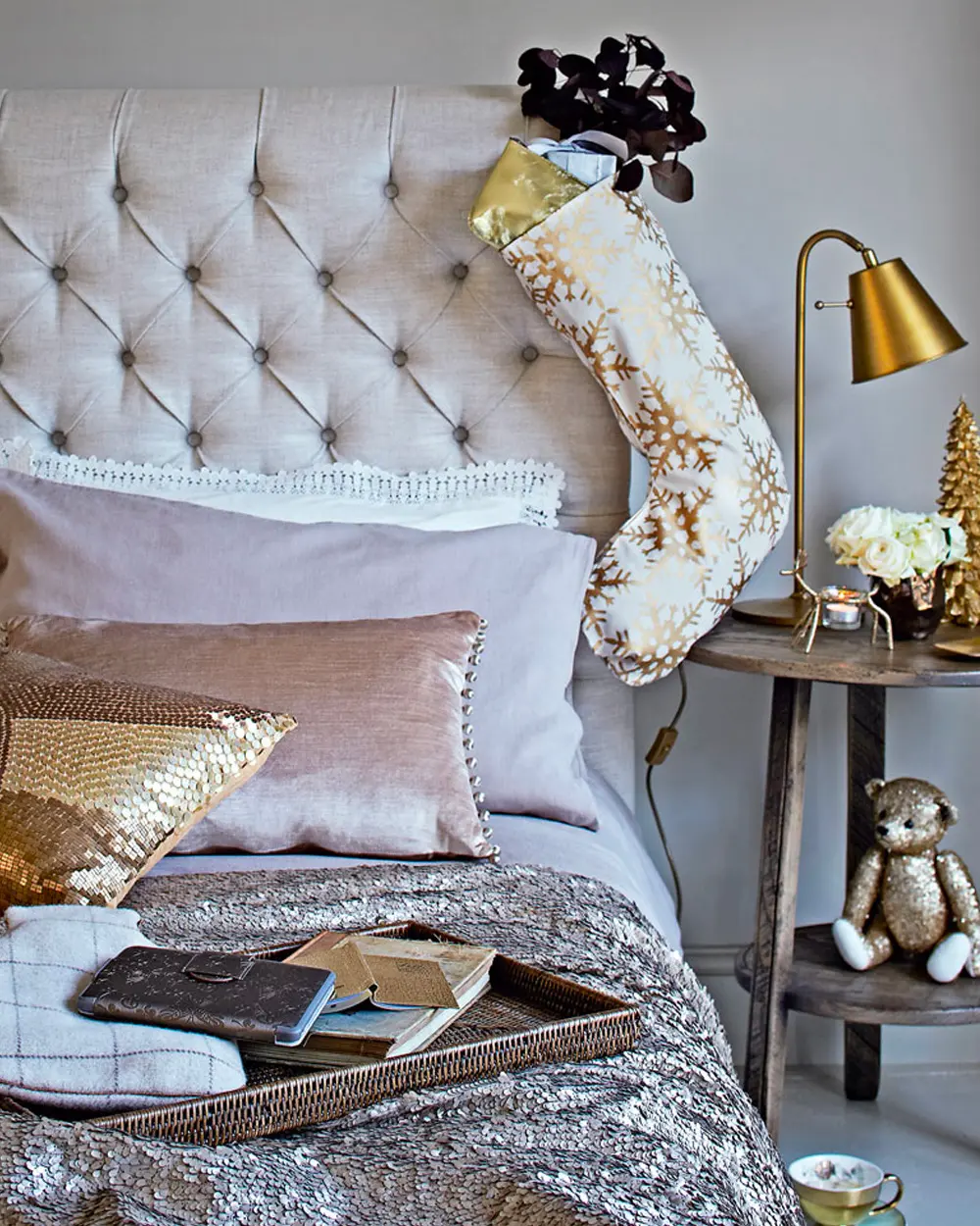 Tufted headboard with velvet pink pillows, a gold sequin cushion, stocking and a brass lamp