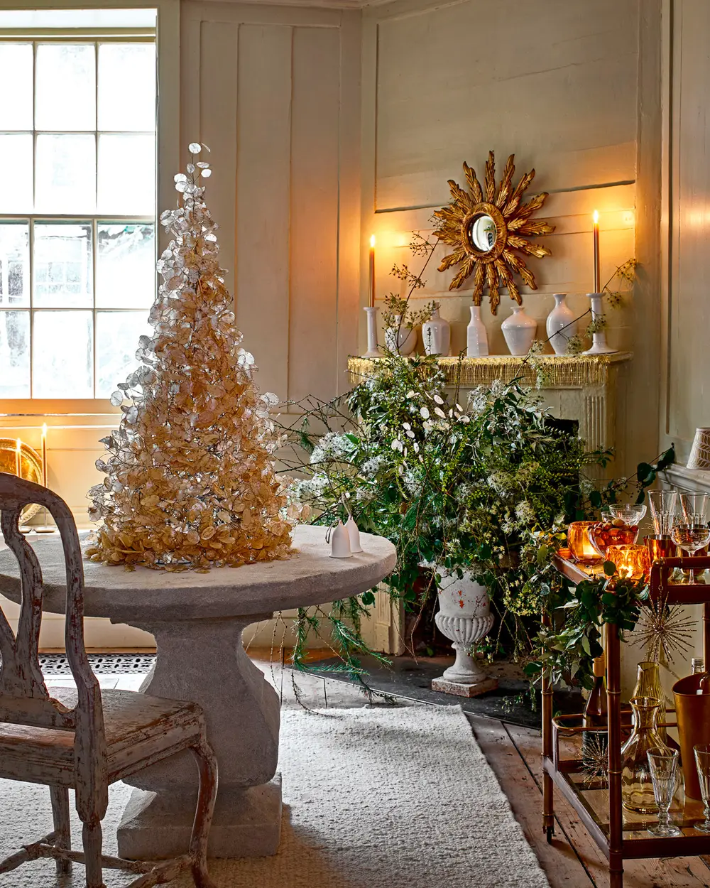 Dining room with a gold tinsel tabletop tree on a stone pedestal table and a sunburst mirror