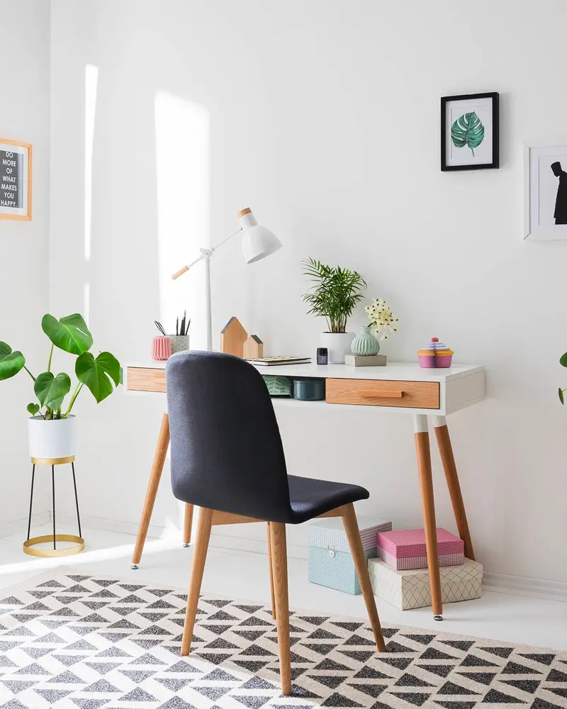 White and wood desk with navy chair, geometric black and white rug and potted plants
