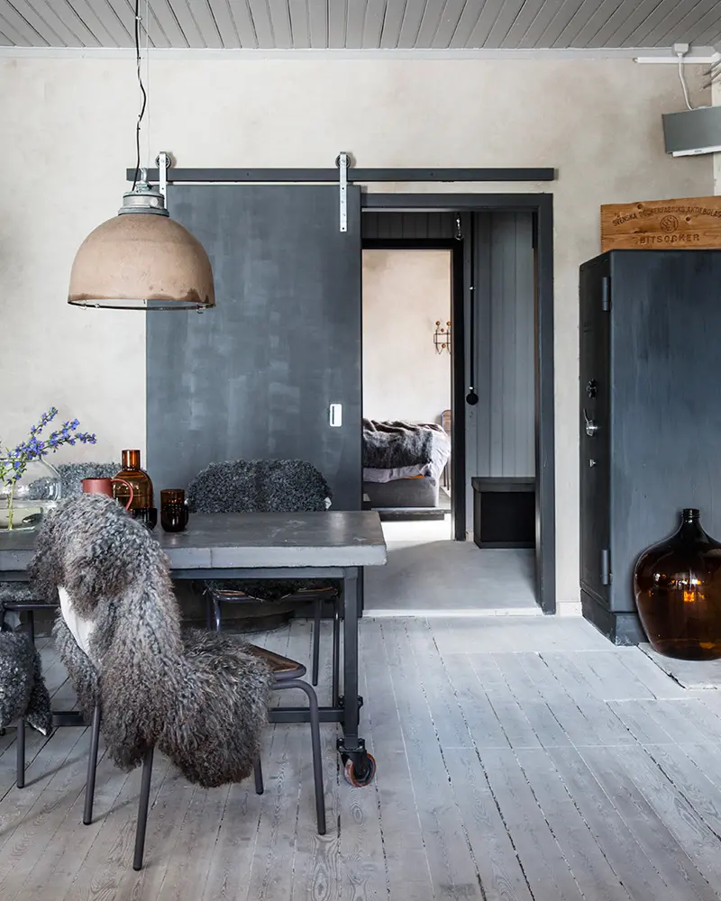 Gray concrete-look walls, a sliding black barn door and a metal table on casters
