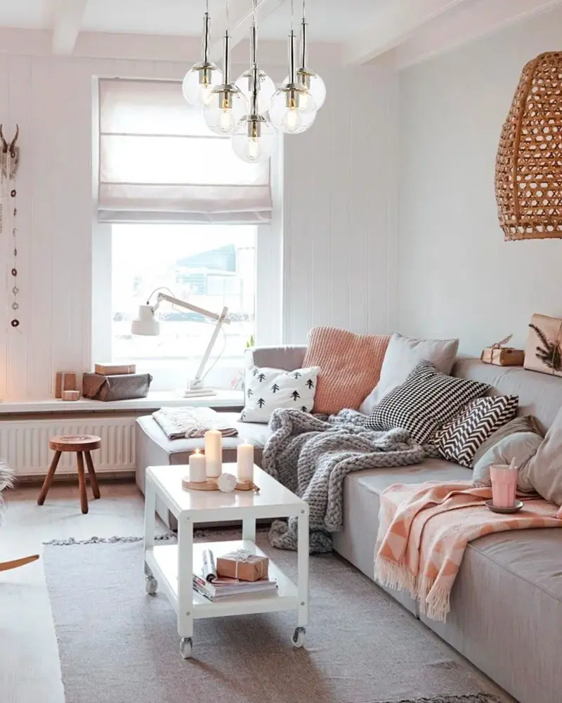 Gray sofa with pink throw and pillows under glass globe chandelier