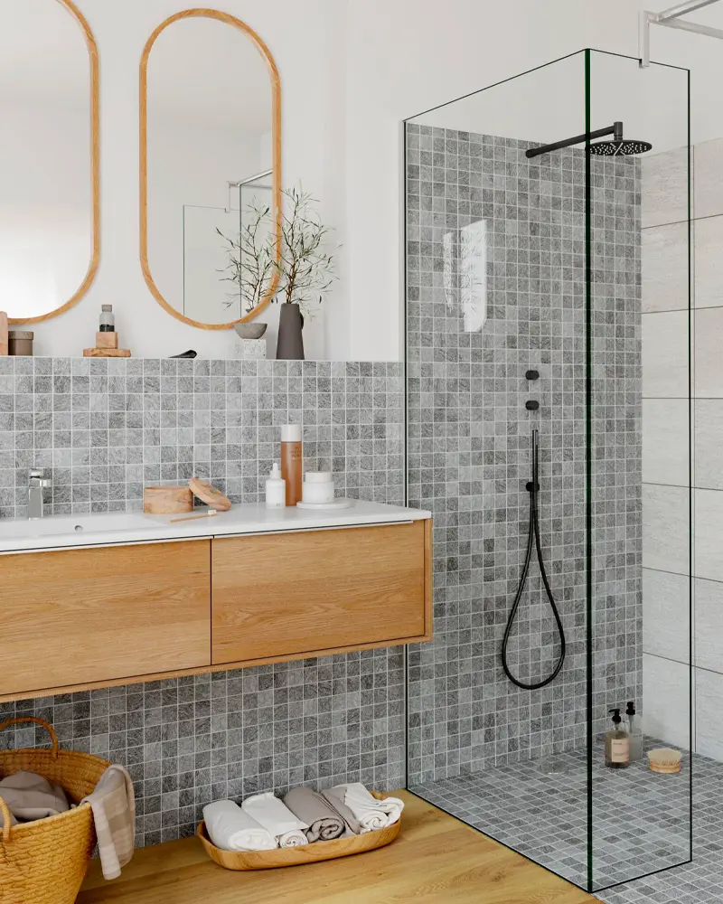 Gray mosaic tile wall with floating oak vanity, two oval wood mirrors and woven baskets