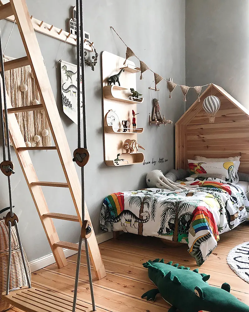 Kids room with gray walls, wooden house bed, climbing ladder and dinosaur shelf
