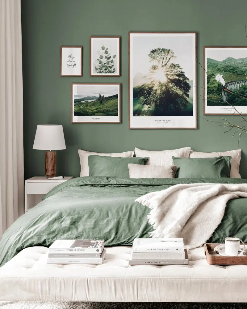Green bedroom with botanical prints, green bedding and a white bench