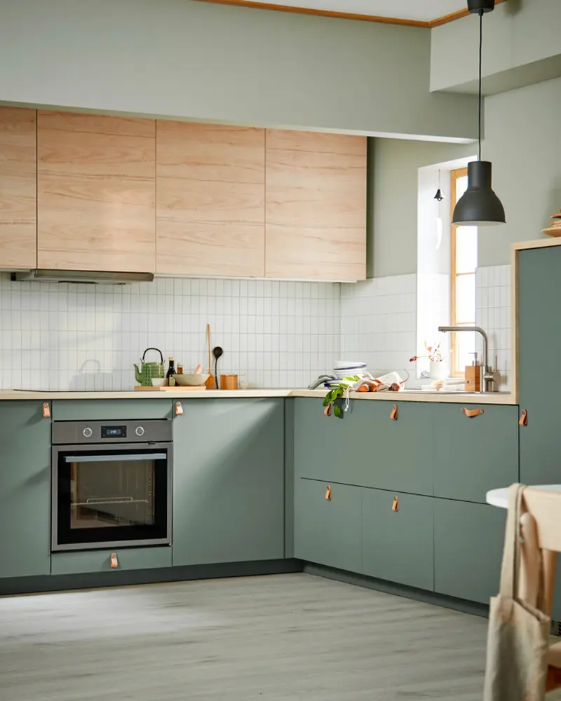 Kitchen with sage flat-front cabinets, wood uppers and white subway tile