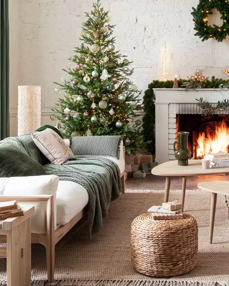 Living room with green tree, white mantel, eucalyptus garland and green throw