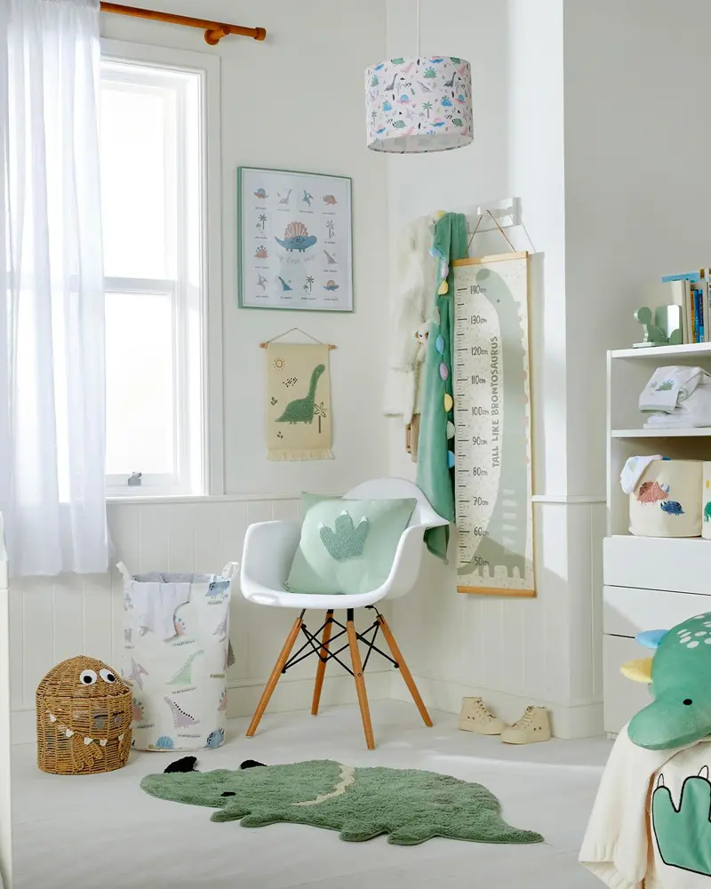 Kids room with white Eames-style chair, dinosaur rug, growth chart and dinosaur pendant