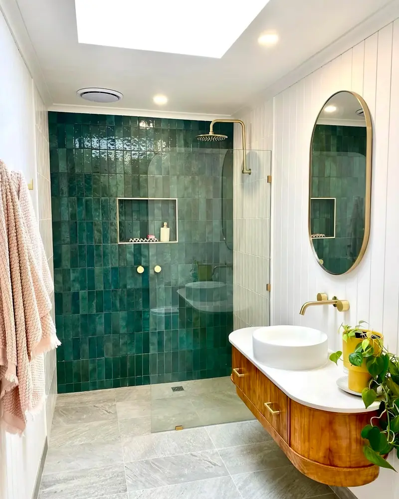 Walk-in shower with green zellige tile and a curved wood vanity