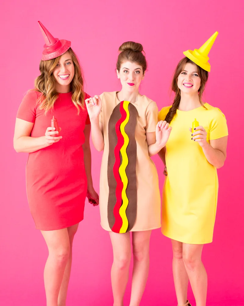 Three women dressed as a hot dog, ketchup and mustard with matching red and yellow hats