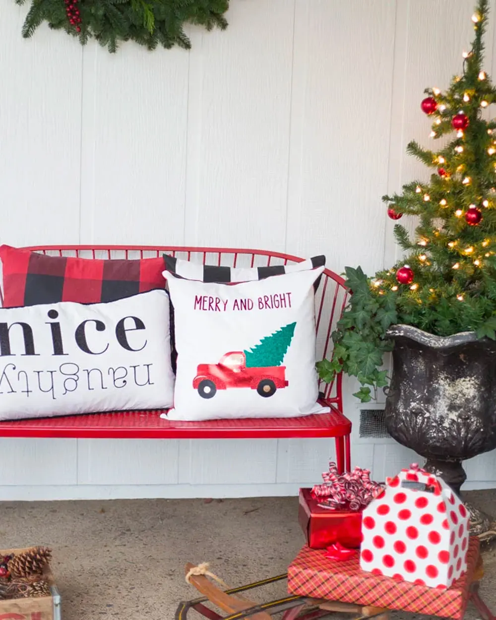 White pillows reading nice/naughty and Merry and Bright with a red truck on a red bench