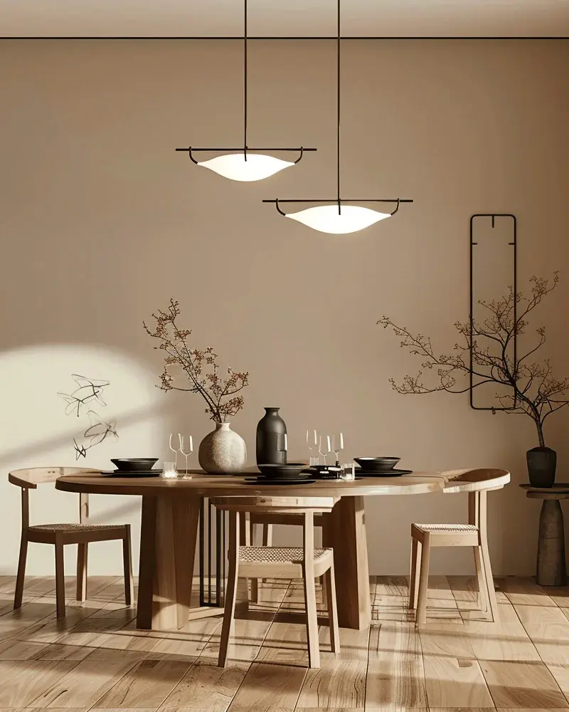 Taupe-walled Japandi dining room with an oval wood table and two disk pendants