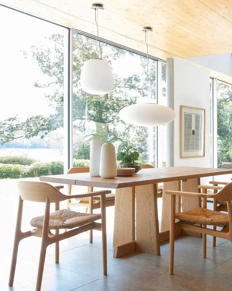 Dining room with a light wood table and chairs in front of large windows