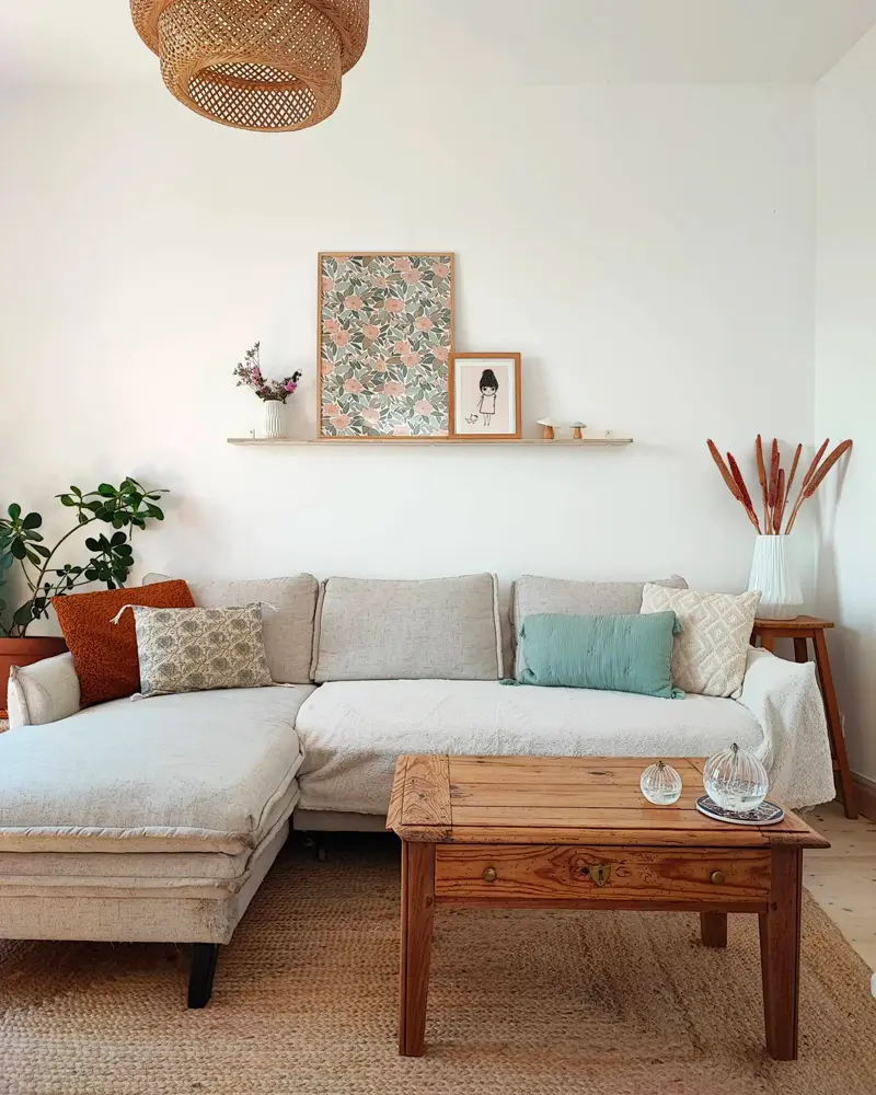 White sectional with rust and teal pillows, rustic wood coffee table, pampas grass and woven pendant
